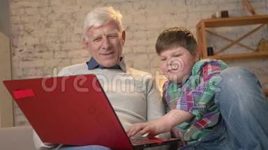 年轻的胖男孩教爷爷如何使用笔记本电脑。 不同的世代。 家庭舒适，家庭闲适，温馨